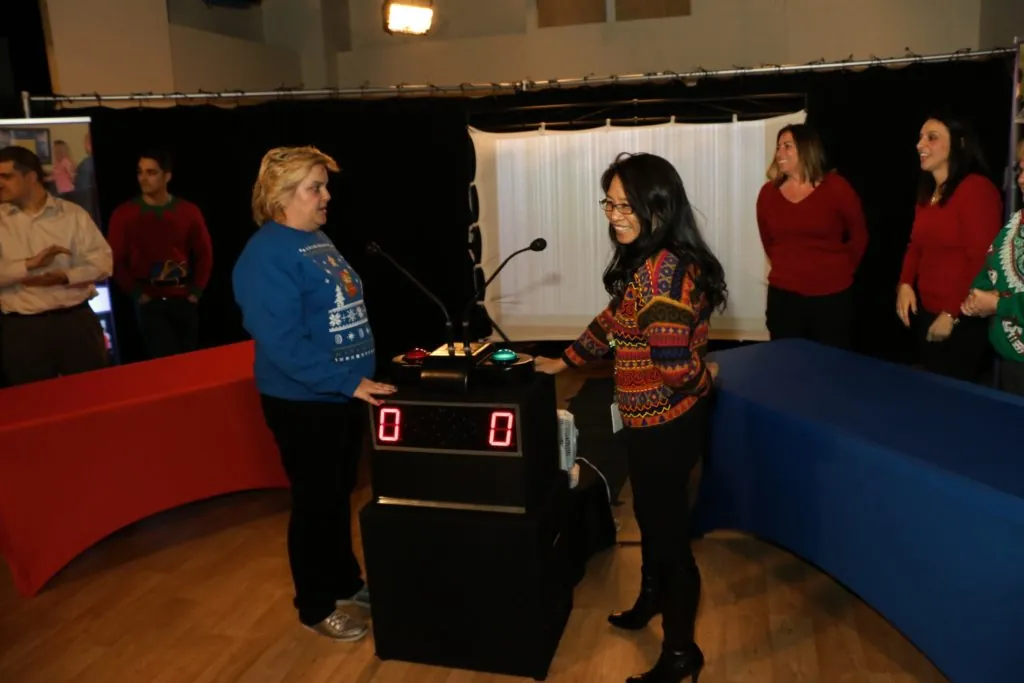 Coworkers face off at the buzzer podium during a hosted holiday game show in New Jersey