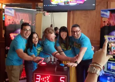 Colleagues in matching shirts press game show buzzers together during a large group game show