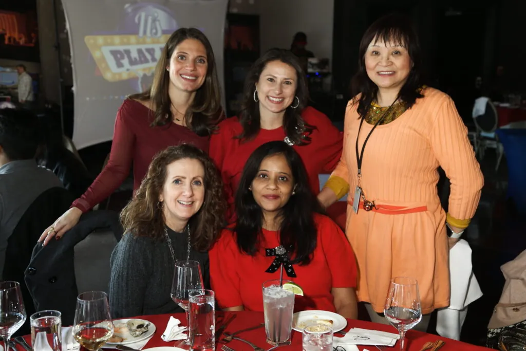 Colleagues smiling together at a table during a corporate team building game show event