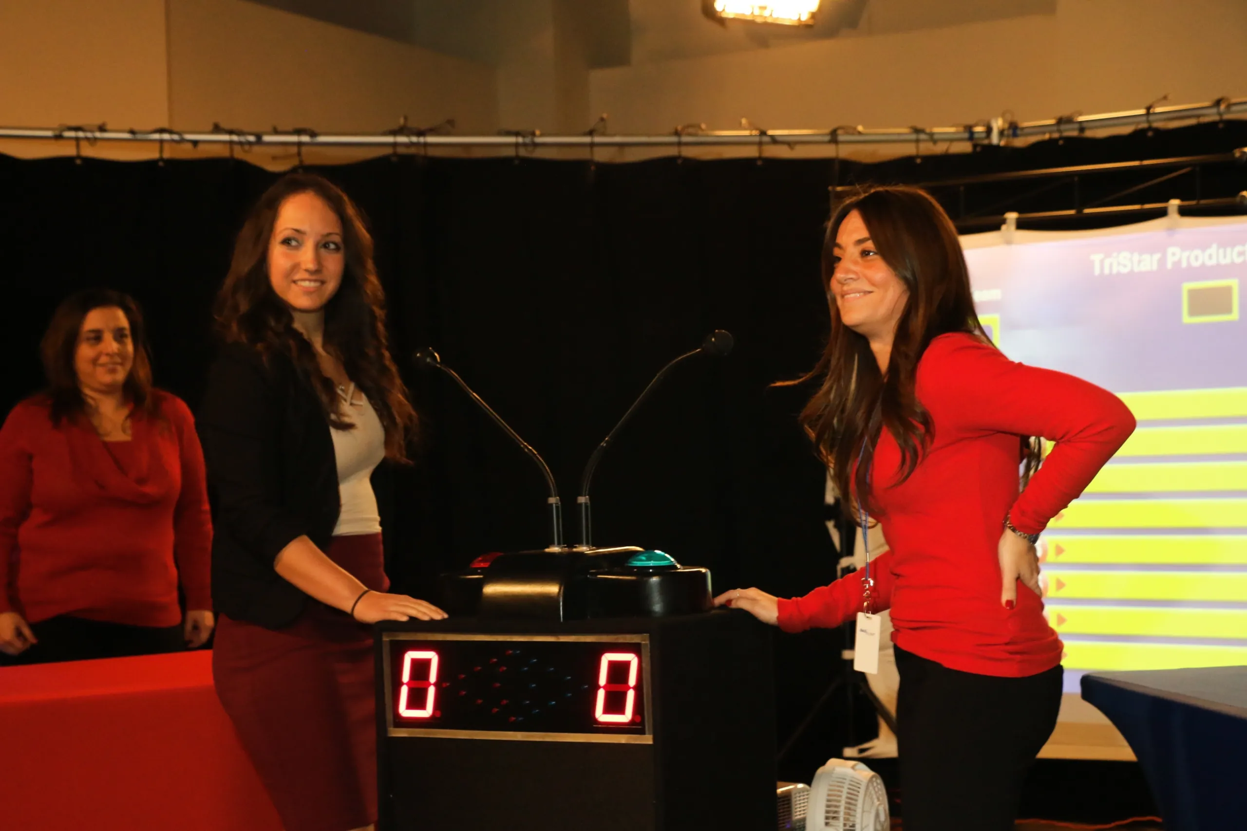 Two players at the Face 2 Face Feud buzzer podium in front of a TriStar Productions game board, score tied at 0 to 0
