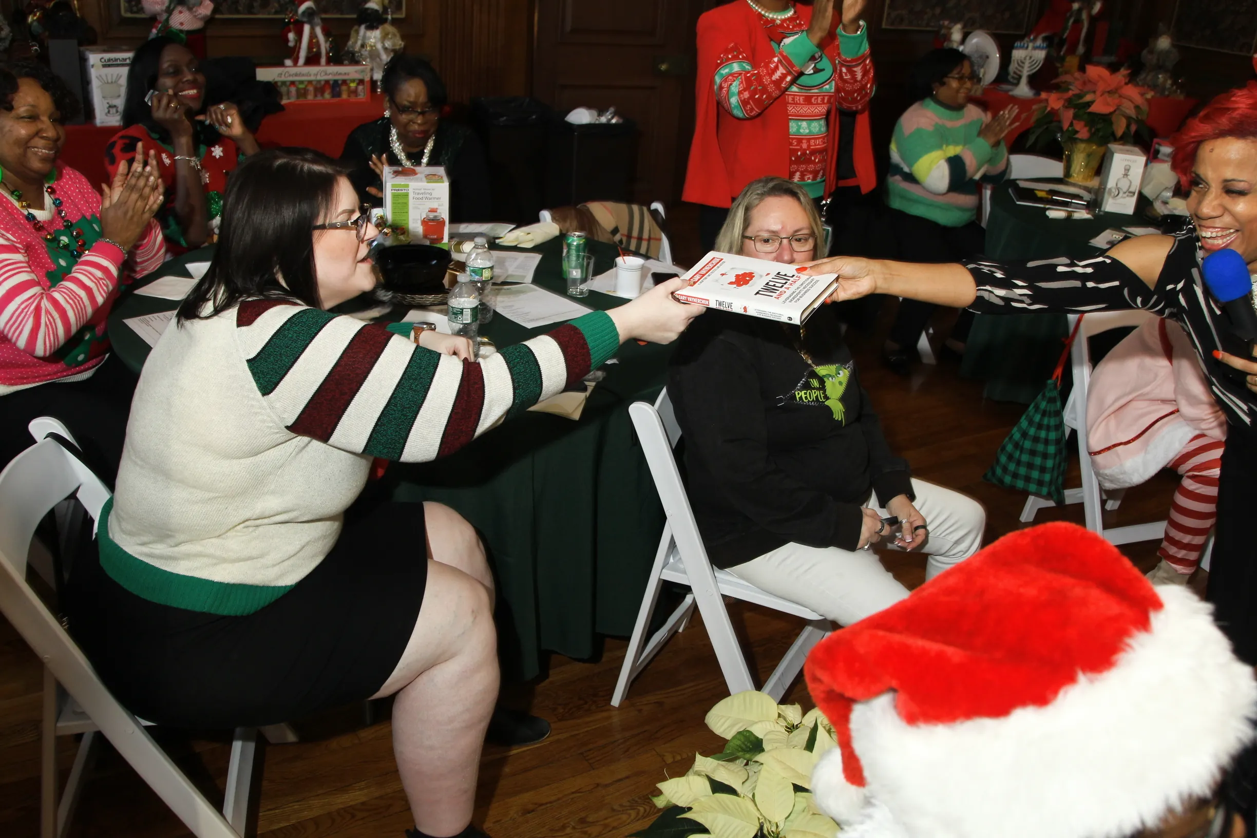 Office Staff Christmas Gala Employees in holiday sweaters play along at their tables during an office Christmas game show